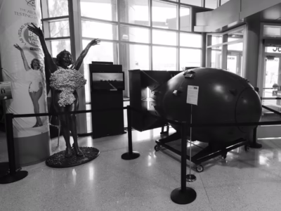 On display at the entrance to the Atomic Museum in Las Vegas. The screen shows a B-29 on the runway at Tinian, from which the atomic bomb missions against Japan were launched. The full-sized statue of the showgirl seems at first to be part of the bomb display but is unrelated.